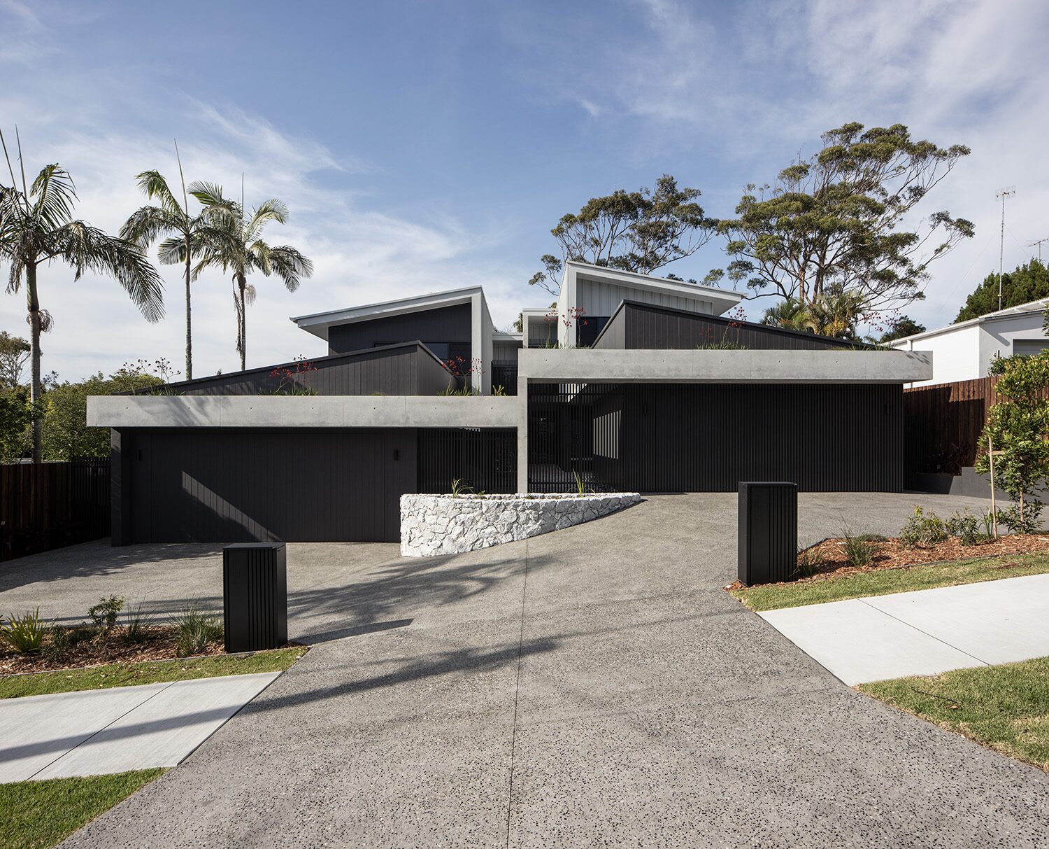 Delorme — front facade, dark cladding and stone garden wall