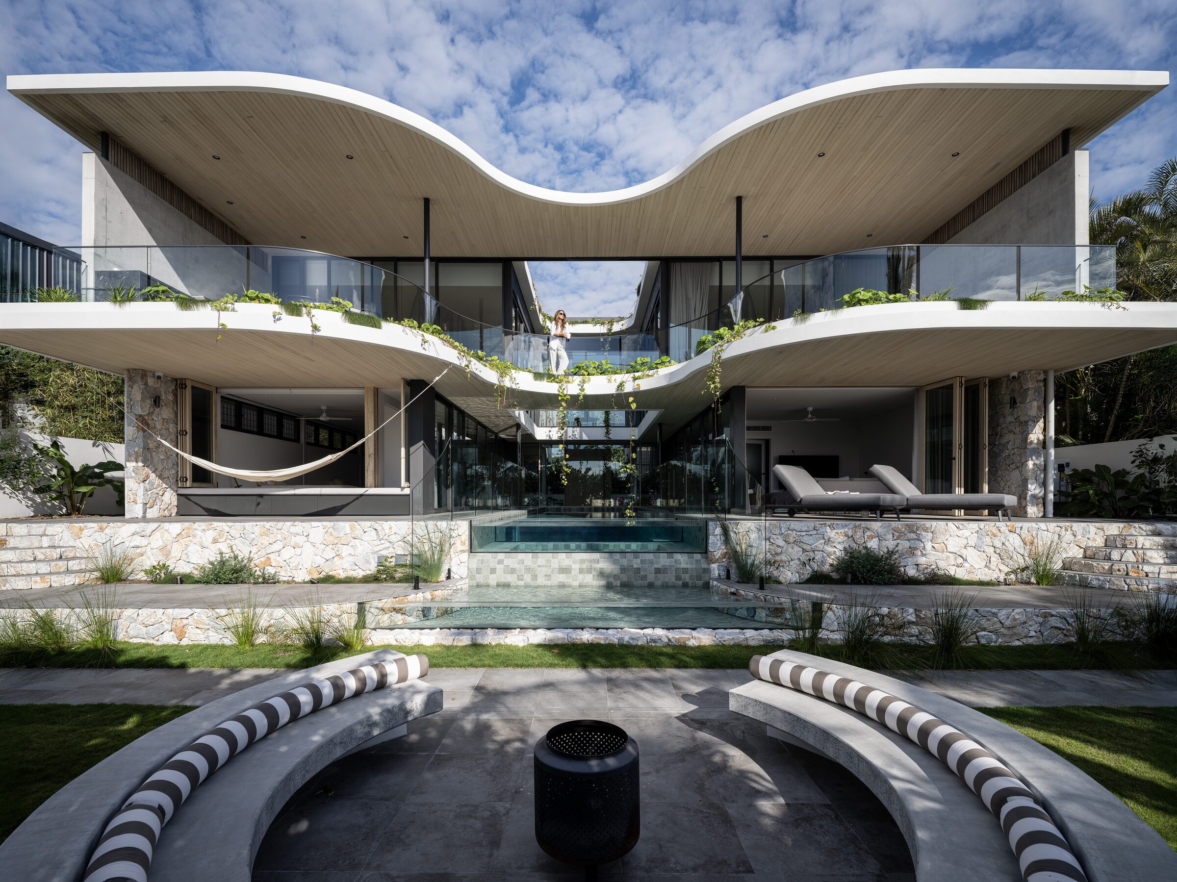 Exterior photograph by Lucas Muro — sculptural residence with pool terrace and curved timber roofline